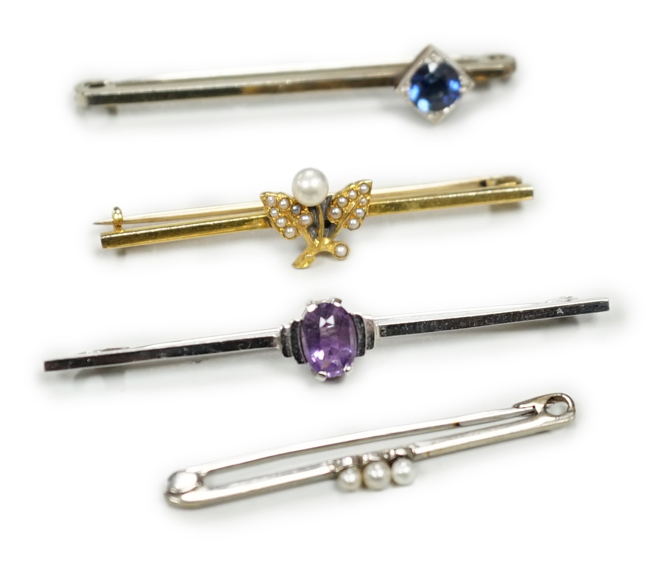 A 9ct white gold and synthetic? sapphire set bar brooch, 45mm and three other bar brooches including yellow metal and seed pearl, white metal and seed pearl and a 9ct and amethyst bar brooch, gross weight 8.1 grams.